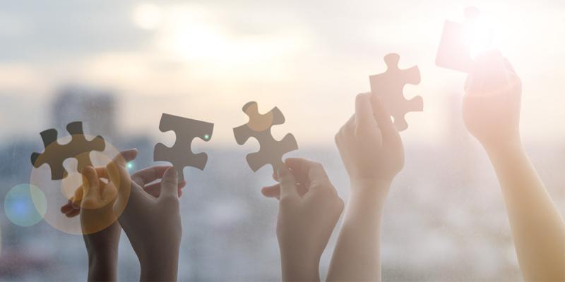 Illustrative image of several hands holding a piece of puzzle each