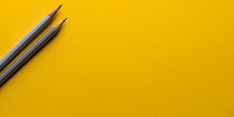 Kuvituskuva: kaksi kynää keltaisella taustalla