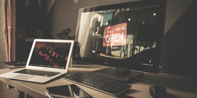 Photo of a desktop with a laptop, tablet and phone.