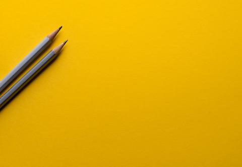 Kuvituskuva: kaksi kynää keltaisella taustalla
